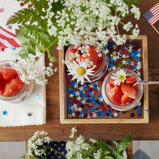 4th of July themed decoration with strawberries on a table with flags and white flowers.
